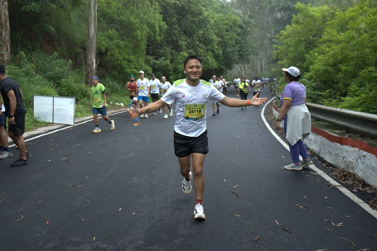 Runner with arms wide open on green road